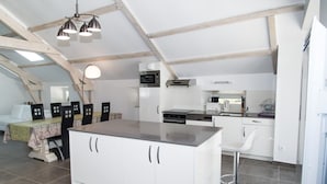 A modern kitchen with white cabinetry, a central island, and a dining area with a table and chairs.