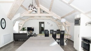 A spacious kitchen with a central island, white cabinetry, and a high ceiling with exposed beams.