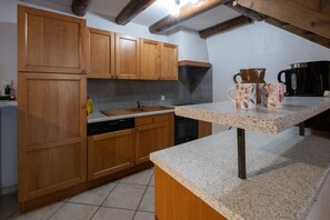 Una cocina con armarios de madera, encimera de granito y cafetera.
