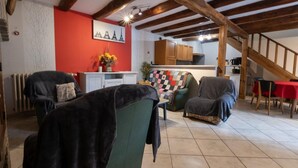 A cozy living room with a fireplace, a dining area with a red table, and a kitchen with wooden cabinets.
