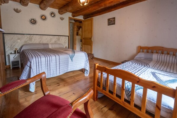 A room with two beds, wooden furniture, a nightstand, and a small table.