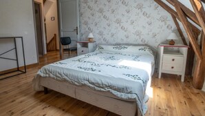 A bedroom with a bed, a chair, a nightstand, and a lamp.