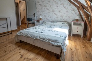A bedroom with a bed, a chair, a nightstand, and a lamp.