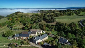 A rural estate with multiple buildings, including a large stone house and smaller structures, surrounded by lush greenery and fields. - Gîtes de France 11 people in Le Teil (ALBARET LE COMTAL)