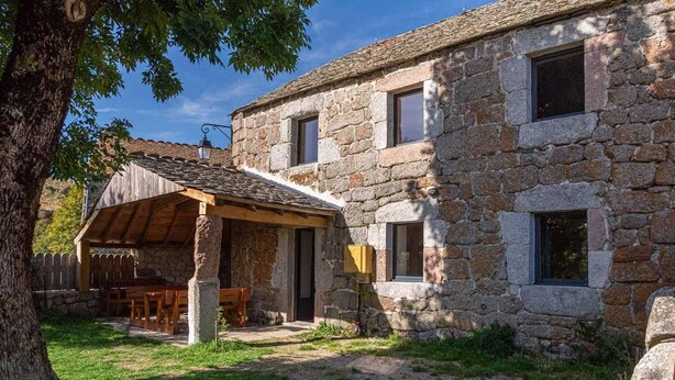 A stone building with a covered patio and a wooden table.