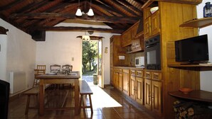 Una cocina rústica con armarios de madera, una mesa de comedor y un televisor.