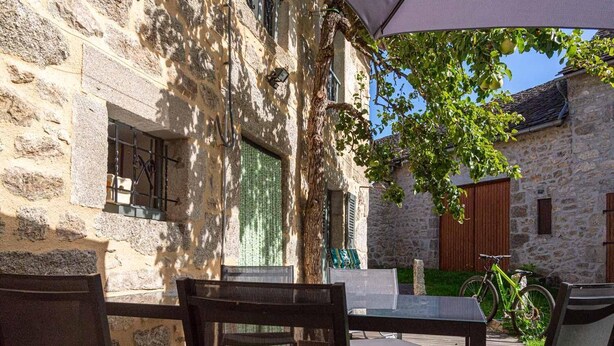 Un edificio de piedra con patio, mobiliario exterior y una bicicleta.