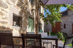 A stone building with a courtyard, outdoor seating, and a bicycle.