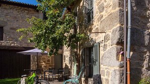 Edificio de piedra con patio que ofrece asientos al aire libre y una bicicleta.
