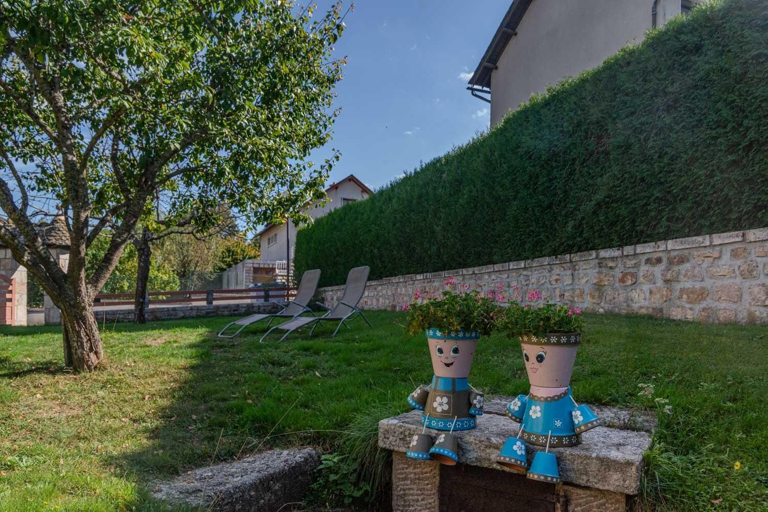 A garden with two decorative planters, a stone wall, and a building in the background.