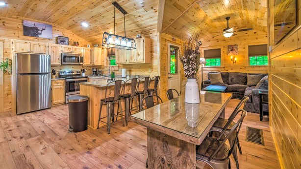 Interior de una cabaña de madera con cocina, comedor y sala de estar.