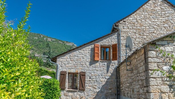 A stone building with two windows, one with shutters, and a satellite dish. - Gîte "Le Noyer" 4 pers in Blajoux (BLAJOUX)