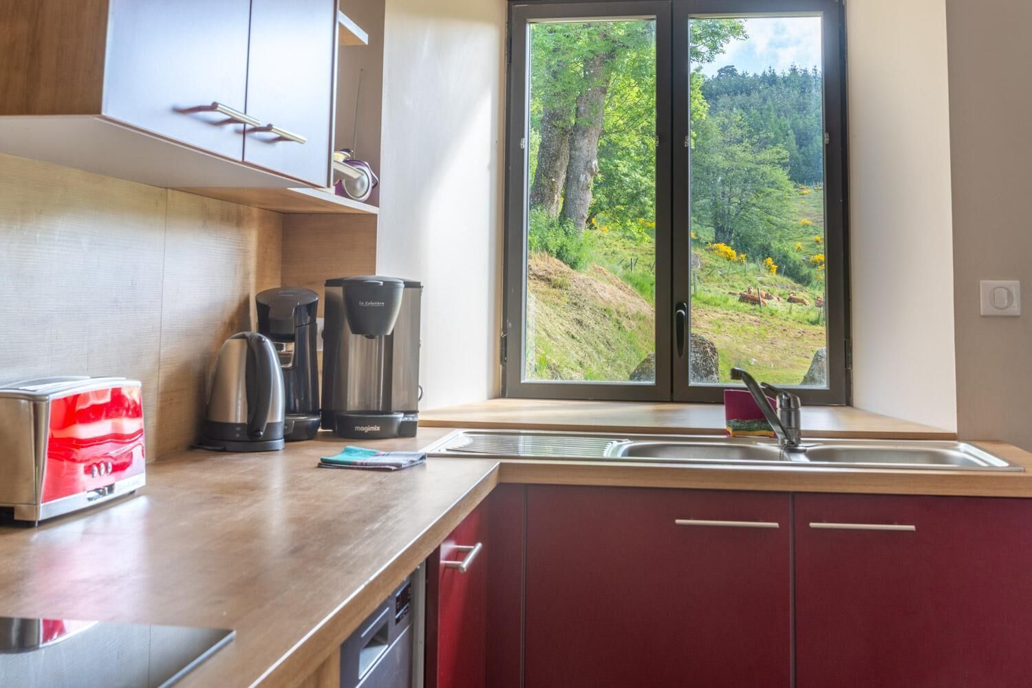 A modern kitchen with a large window, a toaster, a coffee maker, and a dishwasher.