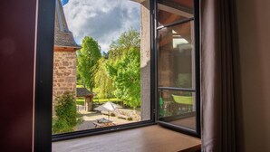 A room with a large window overlooking a garden with a stone building, a gazebo, and a picnic table. - Lzg090a - Gîtes de France 3 Épis 6 Pers à Coulagnettes (SAINT-AMANS)