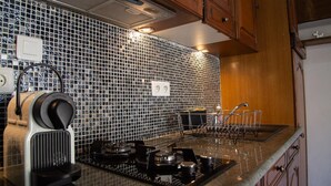 A kitchen with a black and white tiled backsplash, a coffee maker, a stove, and a sink with a dish rack.