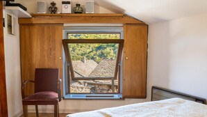 A bedroom with a large window, a chair, a bed, and a radiator.