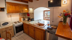 A compact kitchen with wooden cabinets, a microwave, stove, sink, and a dishwasher.