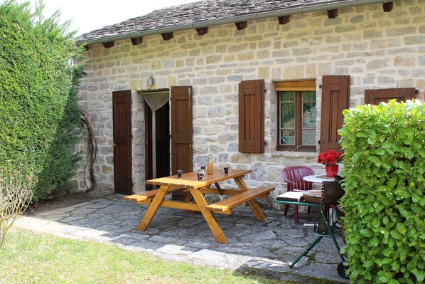 A stone building with a wooden picnic table and chairs outside.