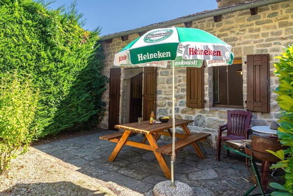 An outdoor seating area with a Heineken-branded umbrella, stone walls, and wooden furniture.
