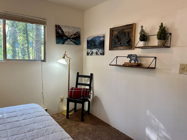 Une chambre à coucher avec un lit, une chaise, une lampe de bureau et des œuvres d’art murales.