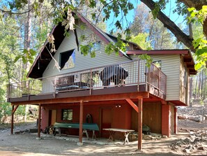 Eine Hütte mit Balkon, einer überdachten Sitzgruppe im Freien und einer Holzterrasse.