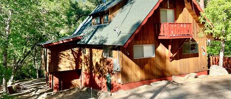 Une cabane en bois avec un toit en pente, un balcon et une petite fenêtre.