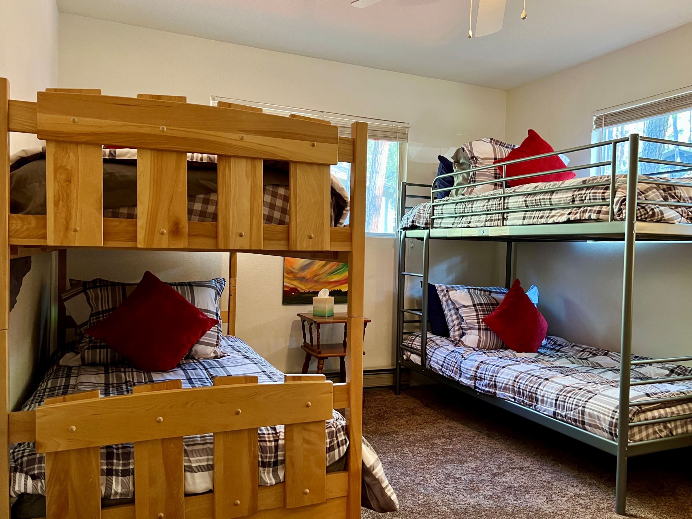 A bunk bed room with a wooden headboard, a small table with a tissue box, and a window with blinds.