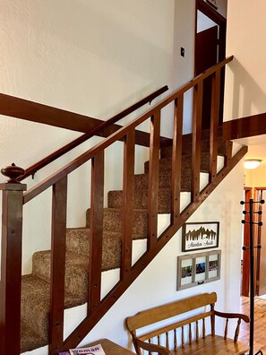 A wooden staircase with a handrail, carpeted steps, and a bench at the bottom. - Creekside Chalet - Prescott Cabin Rentals (Prescott)