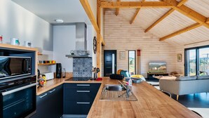 Eine moderne Küche mit Holzboden, schwarzen Schränken und einer zentralen Kochinsel.
