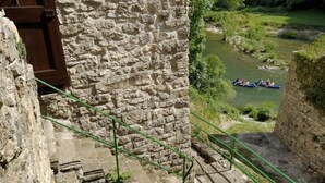 A stone building with a rustic balcony overlooking a river and mountains. - House (SAINTE-ENIMIE)