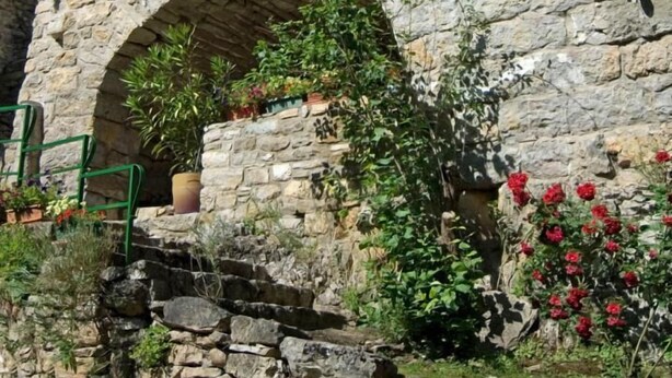 A stone building with a wooden door and an arched entrance. - House (SAINTE-ENIMIE)