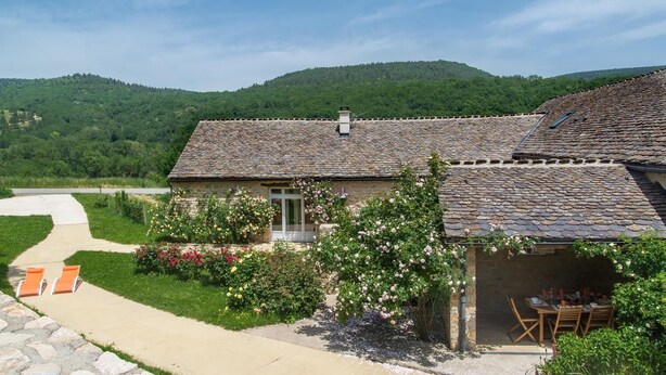 Ein Steinhaus mit Garten, einer Terrasse mit Sitzgelegenheiten und Blick auf grüne Hügel.
