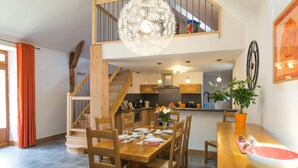Ein Essbereich mit Holztisch und -stühlen, einer Chandelier und einer Küche im Hintergrund.