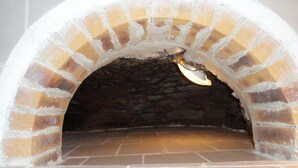 Un horno de ladrillo con interior de piedra y puerta de metal.