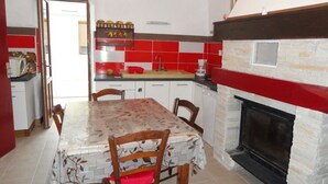 Una cocina con mesa de comedor, sillas, chimenea y un salpicadero de azulejos rojos y blancos.