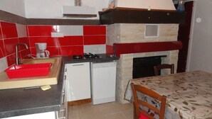 Una cocina compacta con baldosas rojas y blancas, un lavamanos pequeño, una cafetera, una estufa y un lavavajillas.