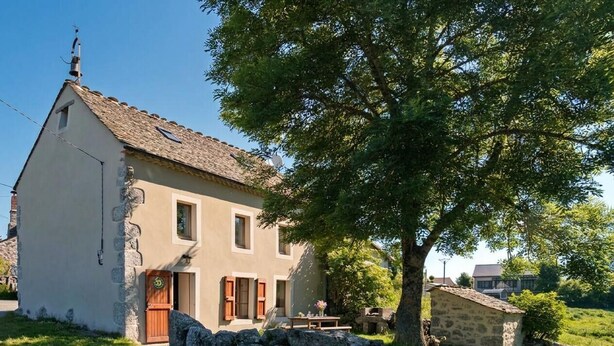 A two-story house with a stone wall, a wooden door, and a stone chimney.