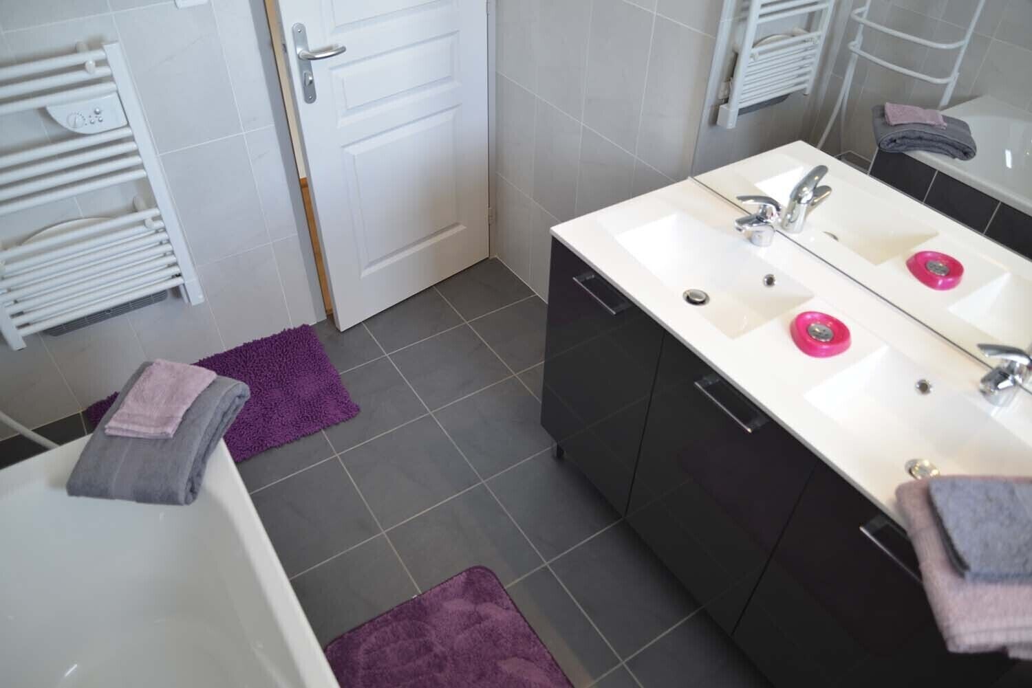 Un baño moderno con dos lavamanos, un espejo y un perchero para toallas.