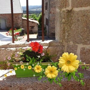 A stone building with a garden in front, featuring red and yellow flowers. - House (SAINT LEGER DU MALZIEU)