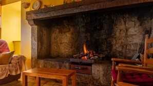 A cozy room with a stone fireplace, wooden furniture, and a clock on the wall.