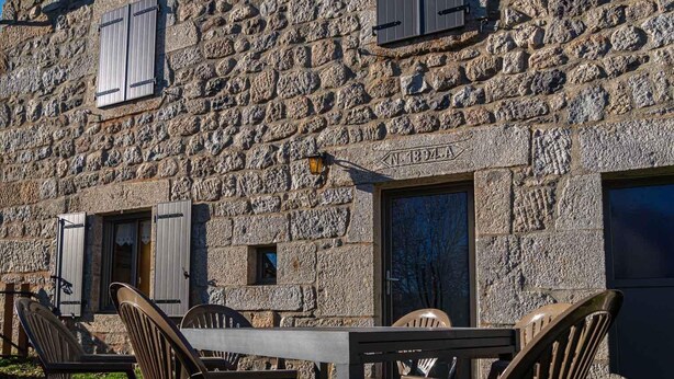 A stone building with a rustic exterior, featuring a table and chairs outside.