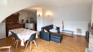A compact living space with a dining area, a sofa, a small table, and a kitchen area.