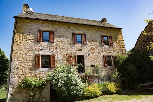 A stone building with a symmetrical facade, multiple windows with shutters, and a small entrance.