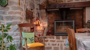 Un muro de piedra rústica con chimenea y una silla de madera con cojín.