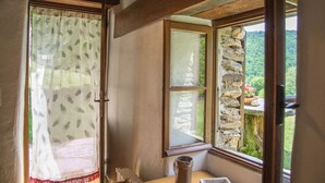 Una habitación con un ventanal grande, pared de piedra y vistas a la vegetación.