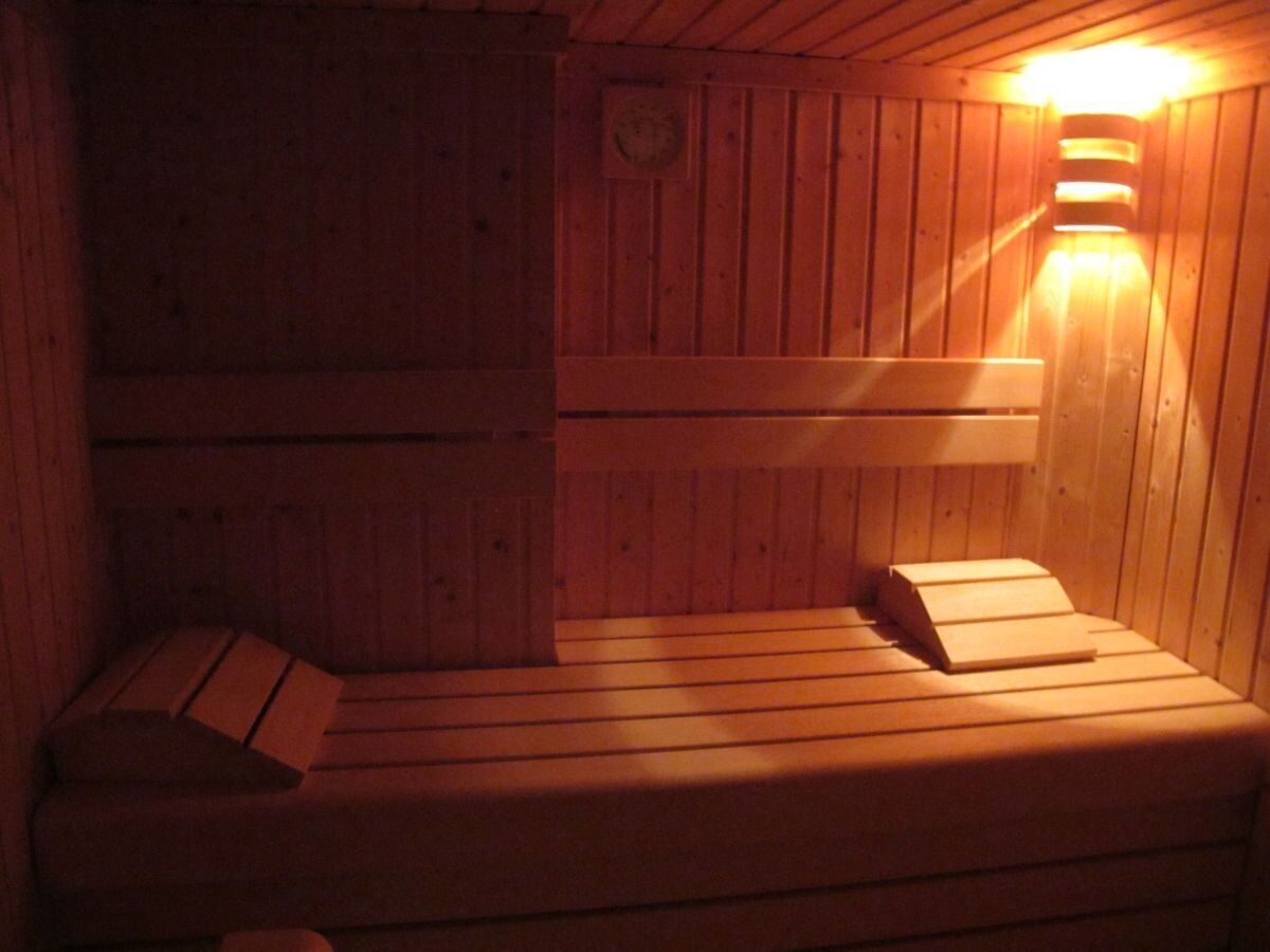 Una sauna in legno con panche e un portalampada a parete.