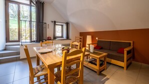Un comedor con una mesa dispuesta para cuatro personas, un sofá y una ventana con cortinas.