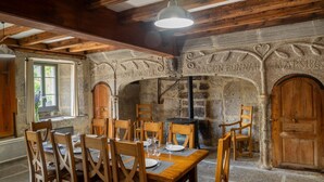 Un comedor rústico con chimenea de piedra, vigas de madera y una araña.