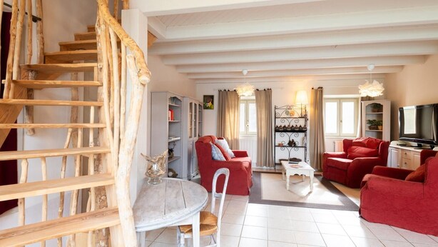 Un salon avec un escalier, des canapés rouges, une table à manger et un téléviseur.