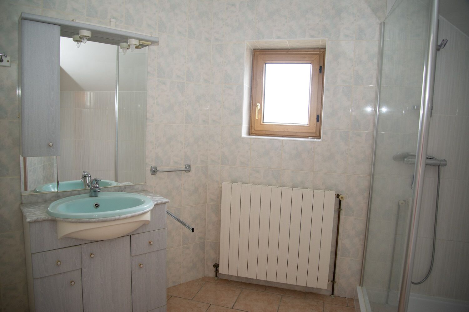 Un bagno con lavandino, specchio, finestra e doccia.